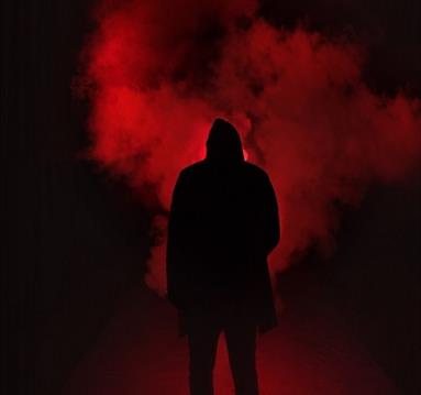 The image shows a black figure stood in red smoke.