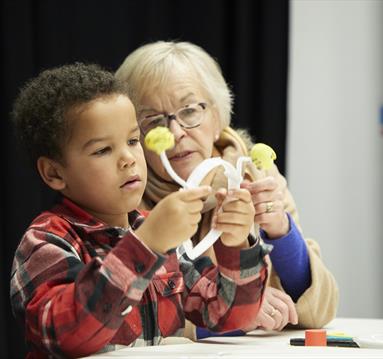 Image shows a child and an older lady looking at a headband which they've made.