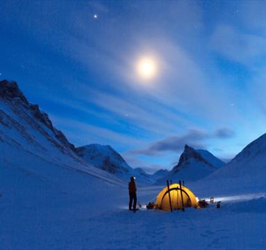 Climber outside tent early in morning before  ascending peak