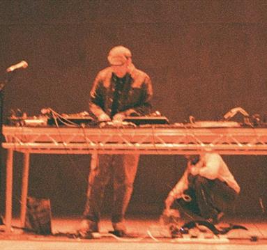 Photo of a performer on a stage playing a DJ set up