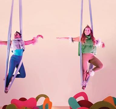 Photo of aerial dancers on stage, held up by aparatus.