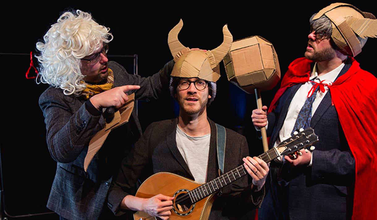 3 men performing with cardboard props