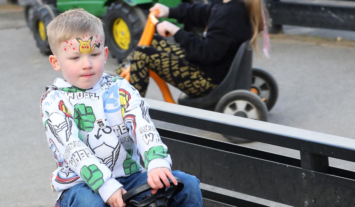 Photo of a young boy on a toy tractor