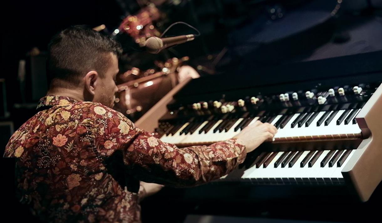 Photo of a jazz piano player from behind.