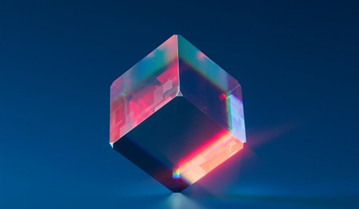 Image shows a clear glass cube with pink and blue lighting inside.