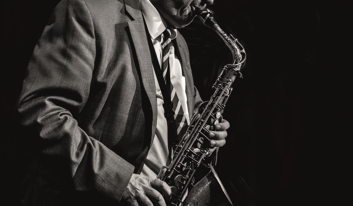 Black and white photo of Alan Barnes playing a saxophone