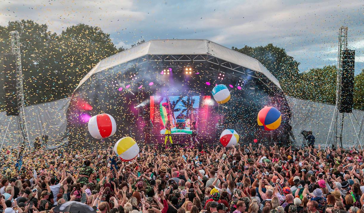 Photo of a music festival facing the stage. In the foreground you can see a large crowd