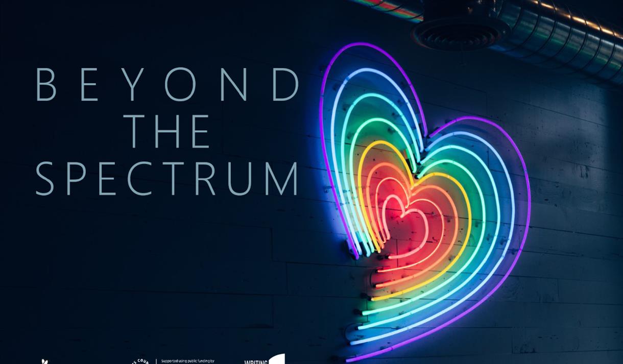 A neon heart with rainbow colours against a dark blue wall