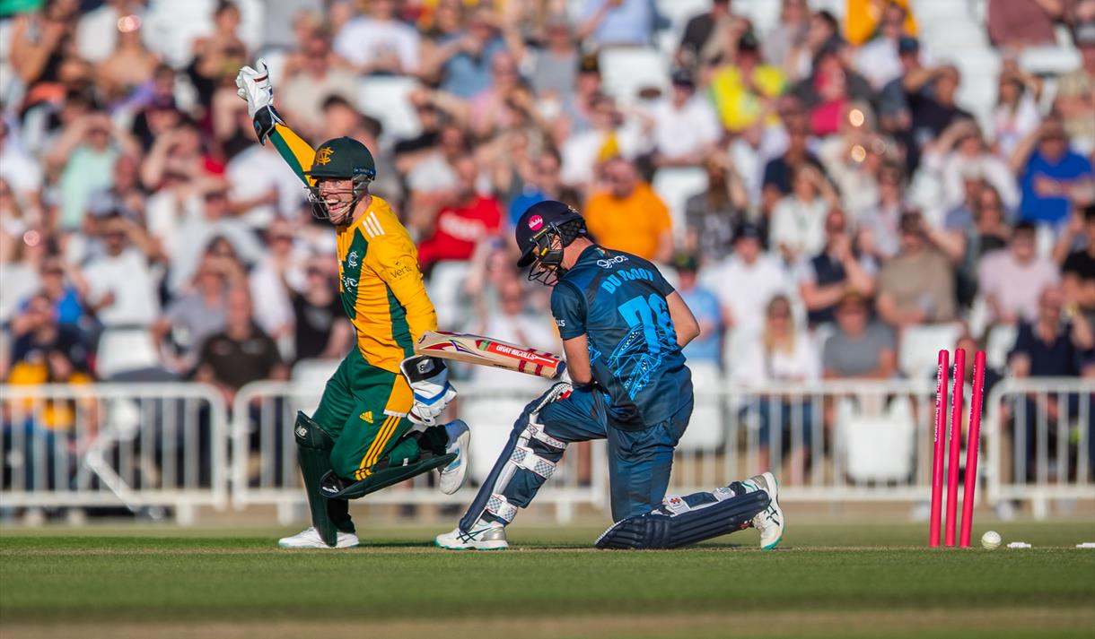 Photo of a cricket match showing two players mid-action