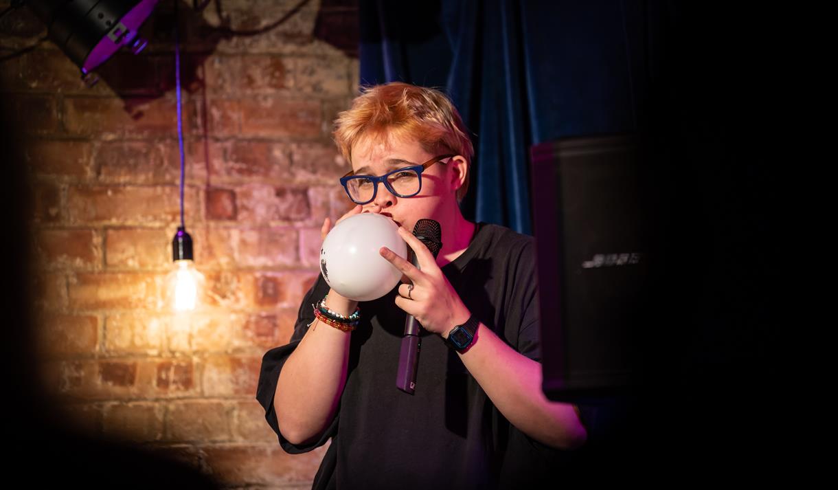 Photo o Cerys Bradley blowing a balloon up on stage