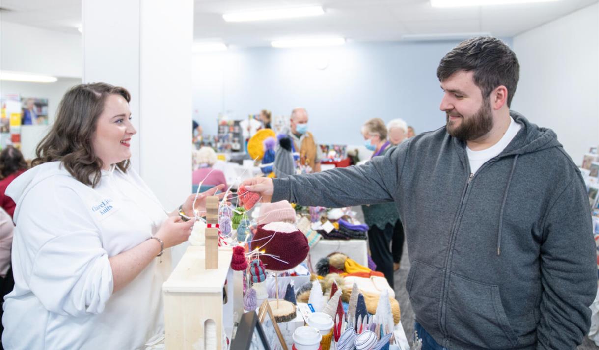 A market stallholder smiling as a shopper browses the stall