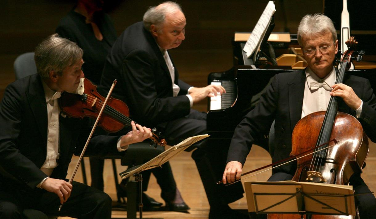 Photo of the Guarneri Trio on stage, playing their instruments