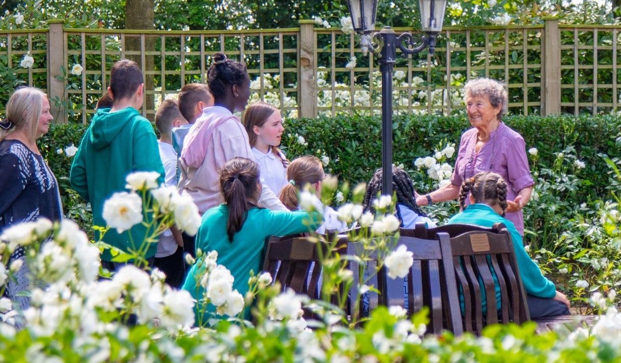 Photo of Holocaust Survivor Hedi Argent MBE with a group of children in the memorial gardens