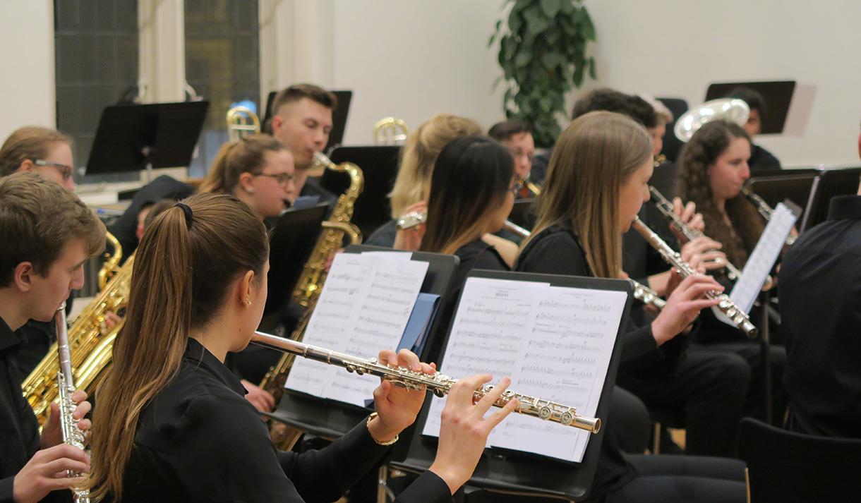 Image shows a group of people playing various instruments with sheets of music in front of them.