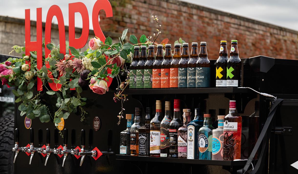 Photo of a drinks cart with bottles of ale and spirits.
