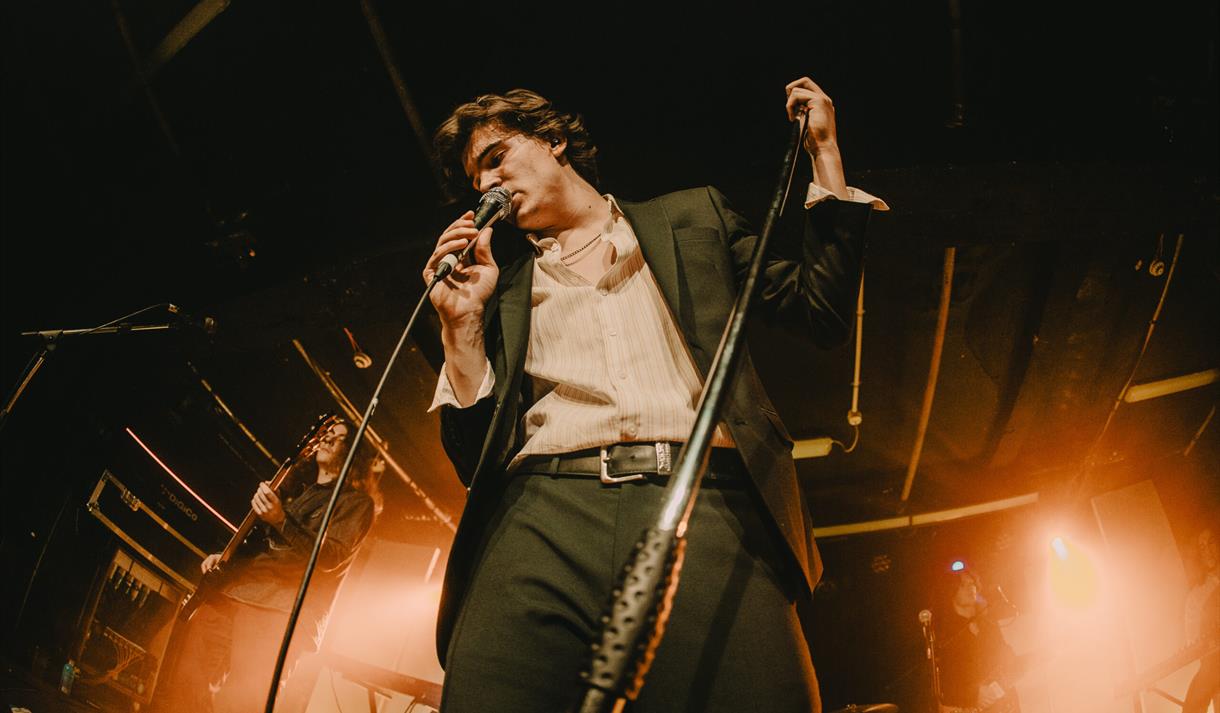 Photo of a singer with bright lights behind them