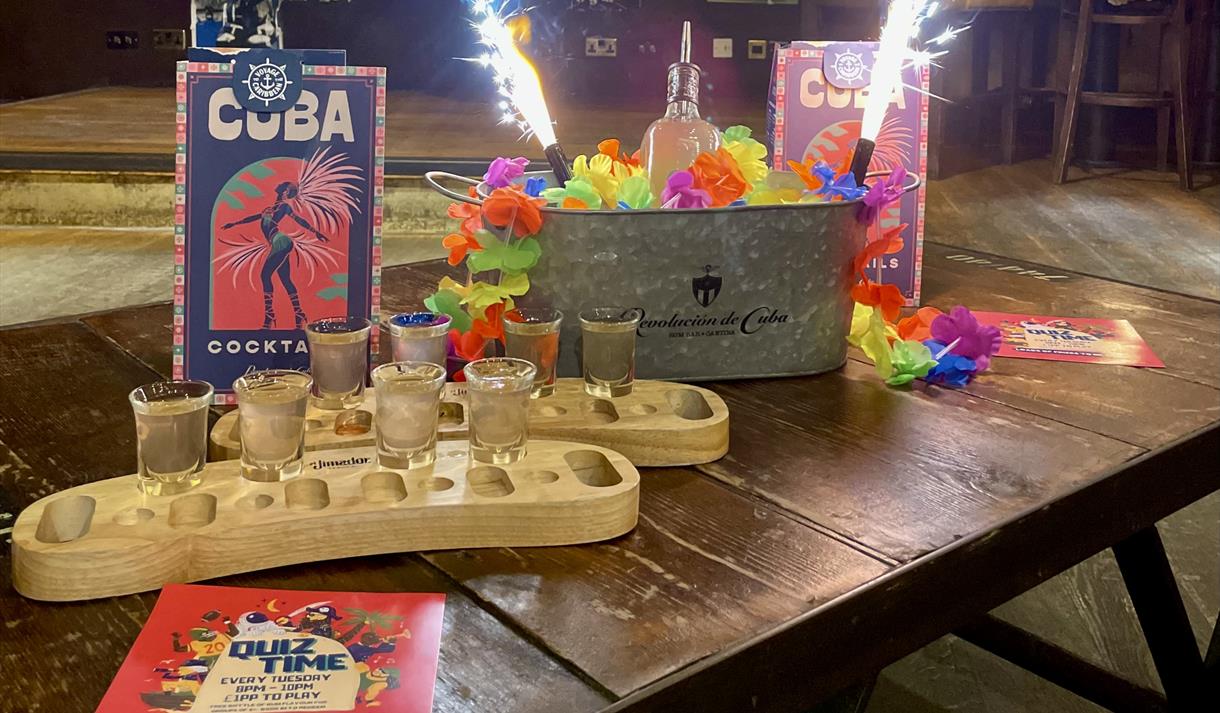 Photo of a bar table with cocktails in wooden trays, drinks menus and sparklers