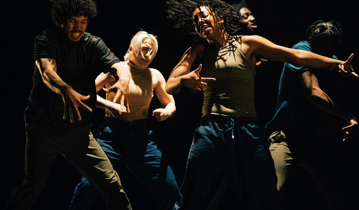 Photo of a dance troupe on stage, in action.