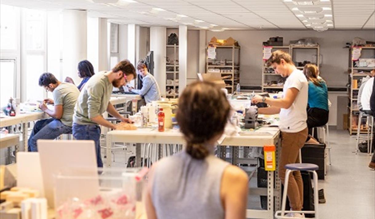 Photo of students in an srt room. Most are busy working or standing at desks, working on their own sculptures.