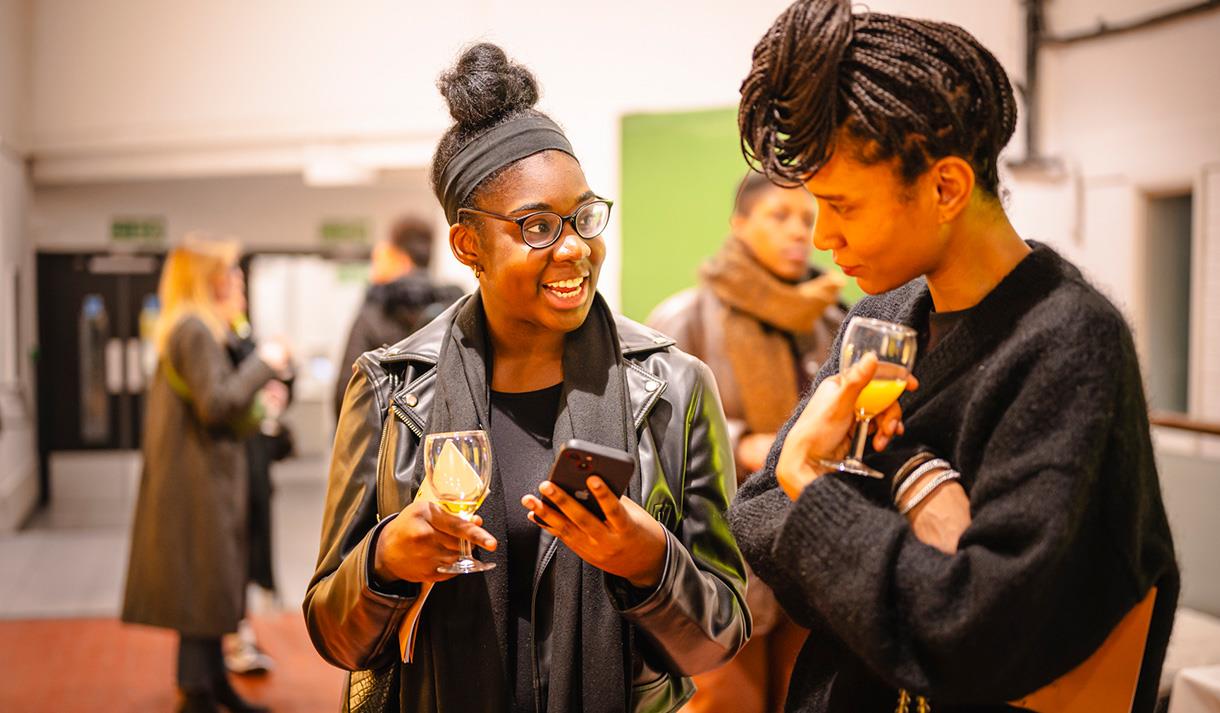 Photo of visitors at an exhibition launch party holding drinks and talking