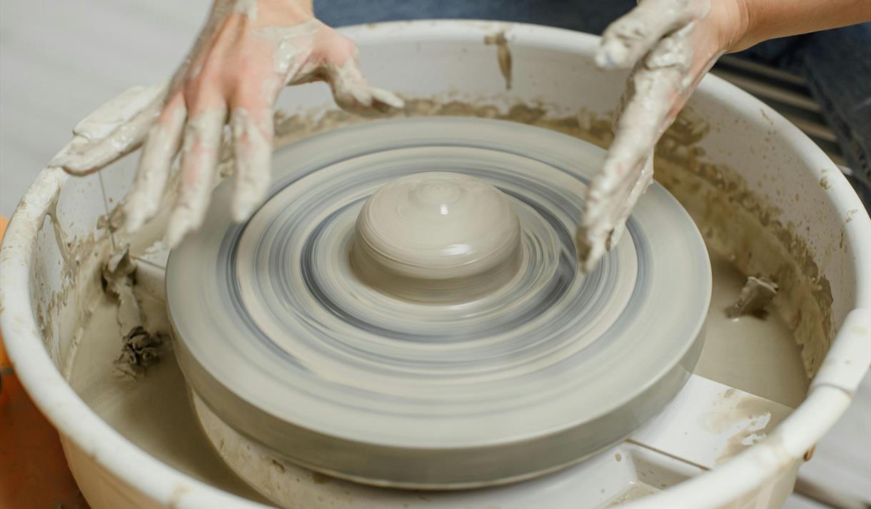 Photo of a potter using a throwing wheel