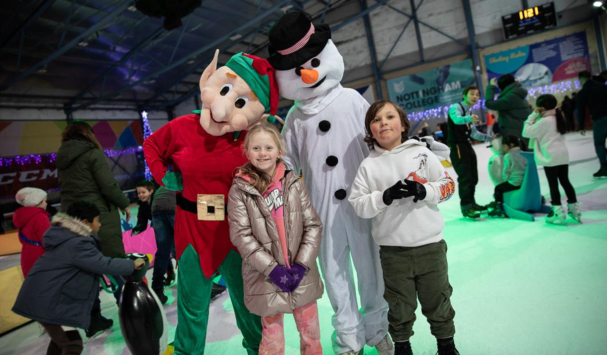 Photo of kids skatingb with costumed characters dressed as Santa's Elf and a snowman