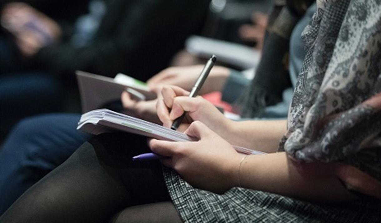 Close up photo of a woman writing something in a notebook.