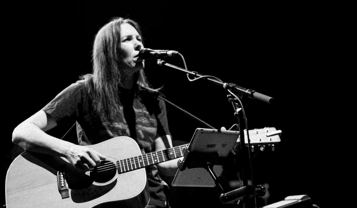 Black and white photo of Thea Gilmore on stage with a guitar