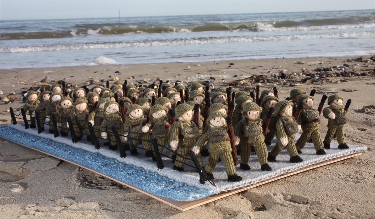 Photo of various knitted soldiers on a beach
