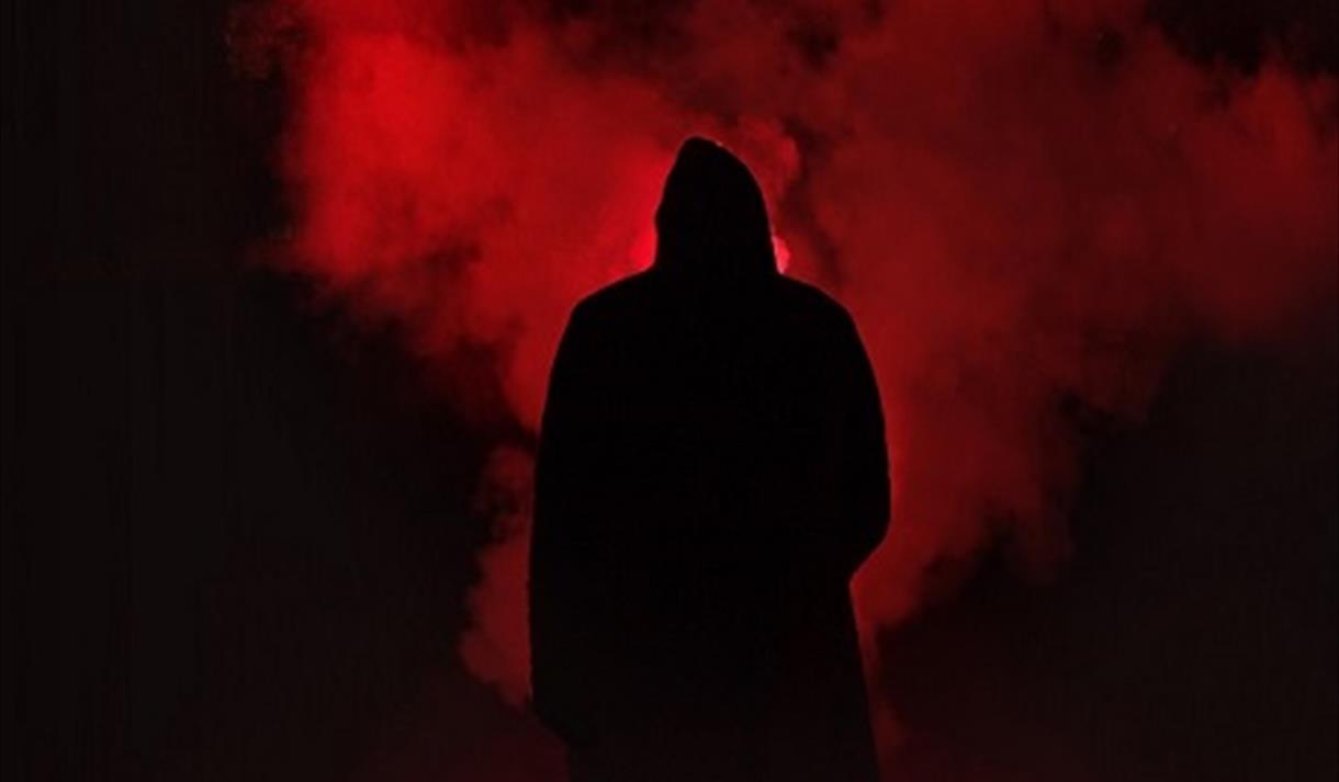 The image shows a black figure stood in red smoke.