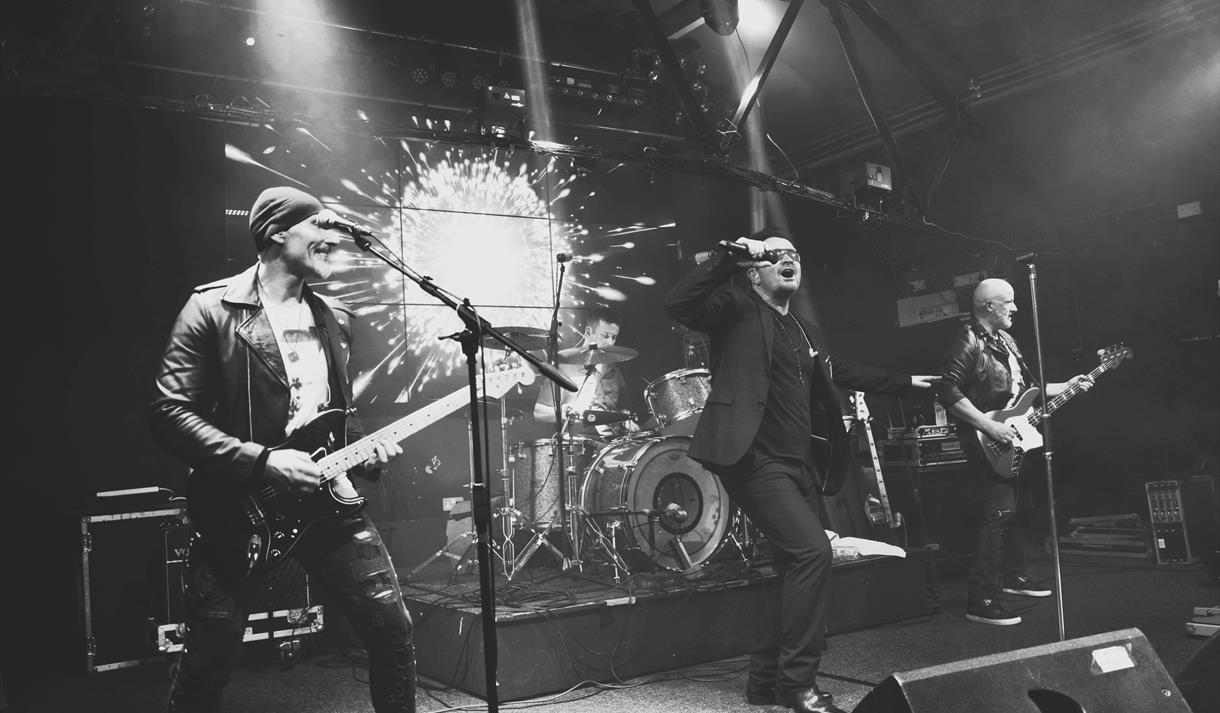 A black and white photograph of a live band performing on a stage.