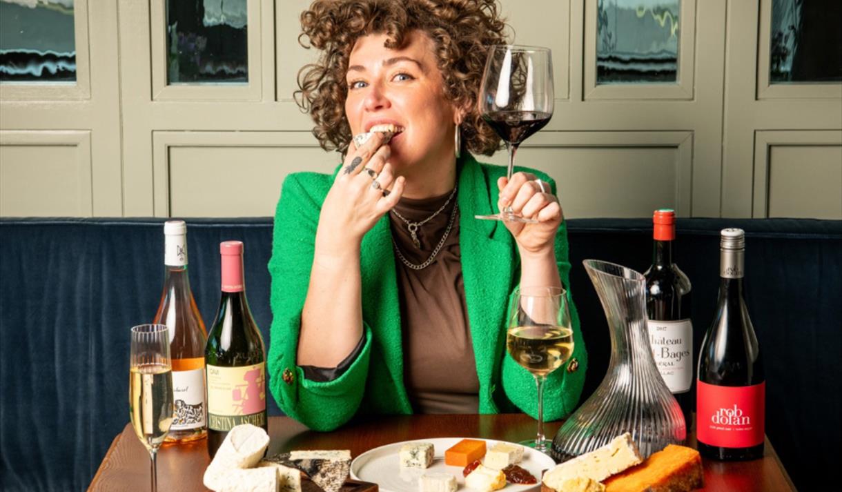 Photo of a woman enjoying a glass of wine with cheese