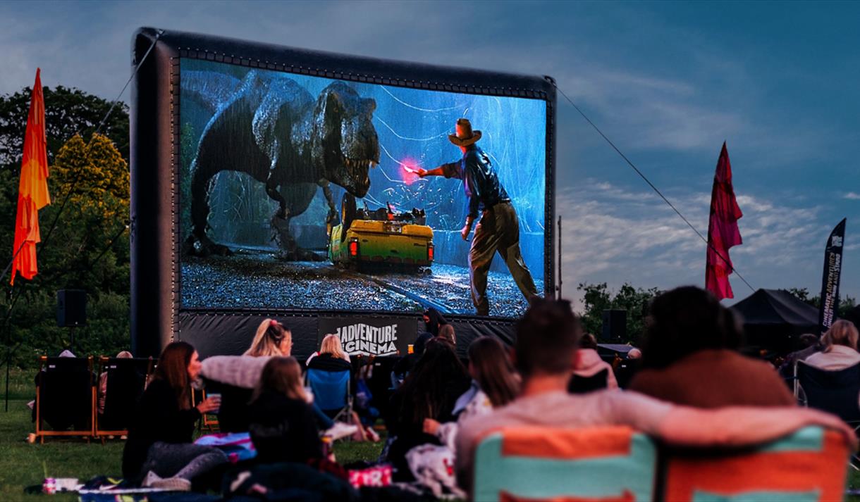 Photo of an outdoor cinema screen showing a still from Jurassic Park.