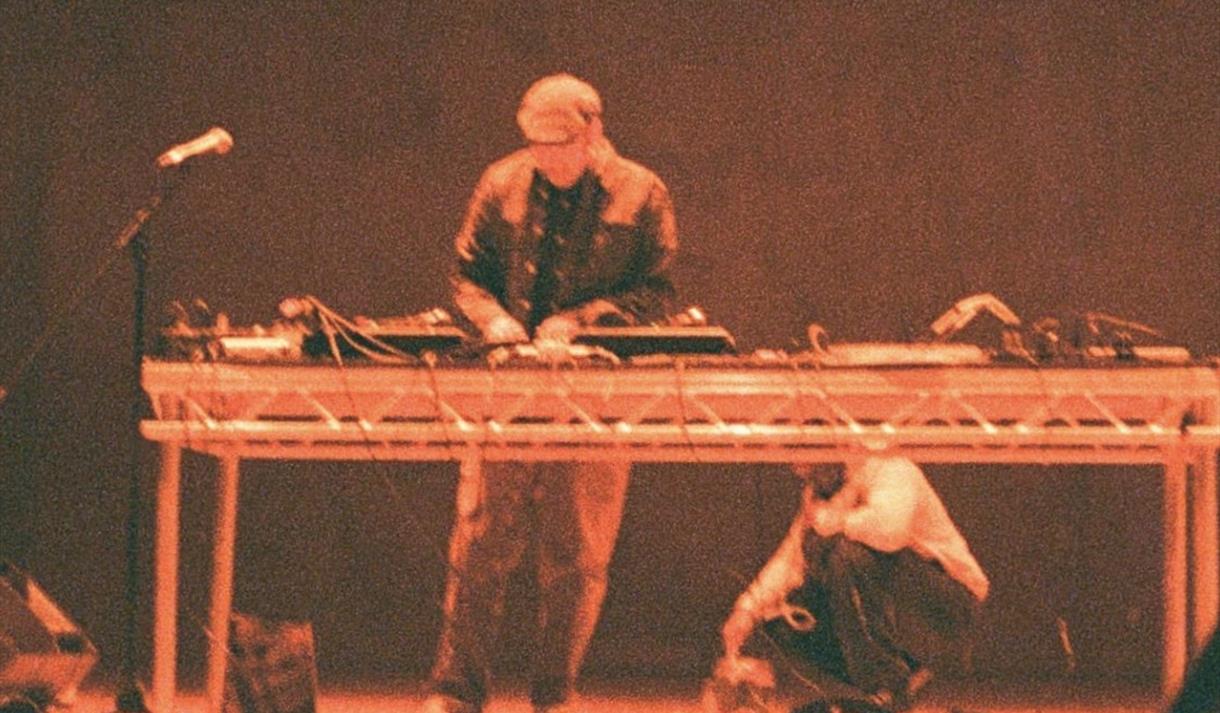 Photo of a performer on a stage playing a DJ set up