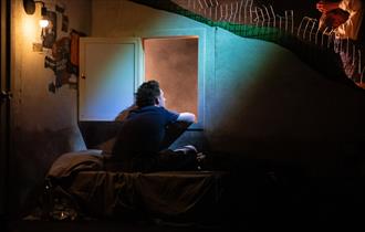 boy on stage production staring out the window