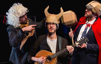 3 men performing with cardboard props