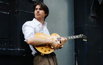 image of connor selby with his guitar
