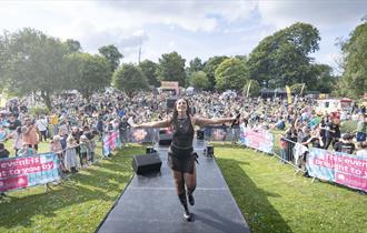 Image from a previous Ashfield Show showing a performer on stage with a large crowd behind them.