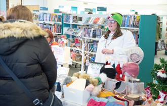 A person talking to a stallholder at a Christmas market