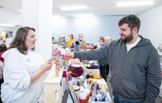 A market stallholder smiling as a shopper browses the stall