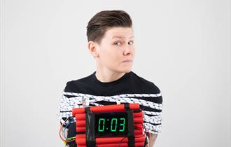 Image of Grace Petrie bound by ropes and holding a bomb that only has 3 seconds before it will detonate.