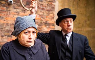 Two costumed actos recreating the scene of a woman at the gallows, with a noose about to be tied around her neck