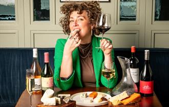 Photo of a woman enjoying a glass of wine with cheese