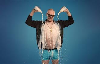 Show poster for Greg Davies new show showing him in underpants with an open shirt, pouring milk on himself.