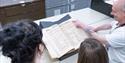 Archives staff showing an old document to two visitors