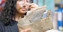 A conservator looks at an old document through a magnifying glass