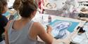 A person painting a self portrait in blue, purple and grey paint