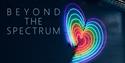 A neon heart with rainbow colours against a dark blue wall