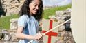 A young child stands holding a wooden sword and St. Georges Cross shield