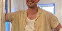 A man in a yellow short and green trousers smiles